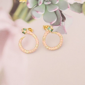 Detailed close-up of golden snake stud earrings with pink enamel and green gemstone eyes
