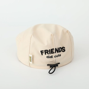 Close-up of beige cotton beret featuring black FRIENDS embroidery and adjustable drawstring