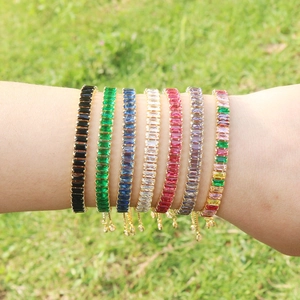 Detail of colorful tennis bracelets with rectangular zircons on a green background