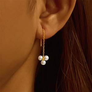 Detailed macro shot of long gold chain tassel earrings with three white pearls for women