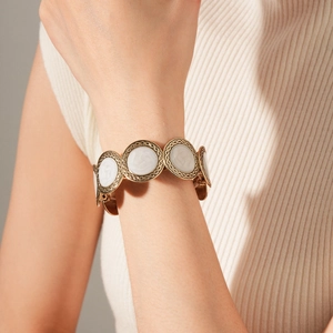 Detail of a vintage gold leopard-style bracelet with white enamel on a model's wrist