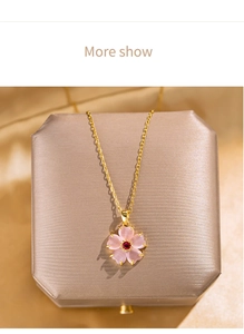 Detail view of gold floral necklace with pink petals and cat eye stone on a jewelry box