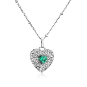 Macro shot of silver heart necklace with a green central stone and white pavé setting