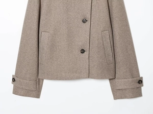 Détail du manteau en laine camel montrant la poche latérale et le poignet boutonné