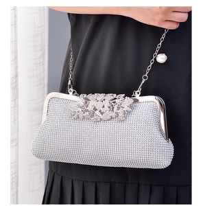 Detailed view of silver evening clutch featuring rhinestone leaf clasp and pearl chain strap
