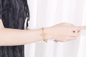 Detail of gold cross bracelet with white zircon stones and stylish OT clasp closure
