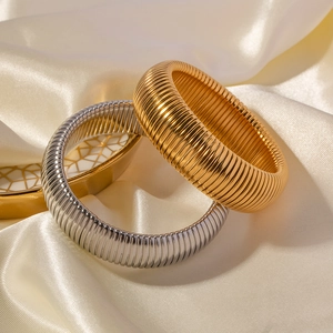 Detail von vintage gold- und silberfarbenen elastischen Tubogas-Armreifen auf Seide