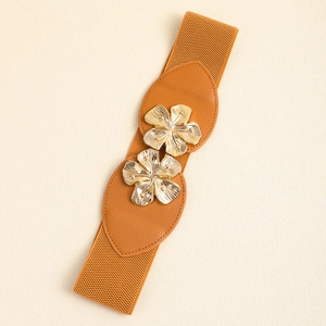Close-up of golden flower metal buckle on elastic brown leather belt for women