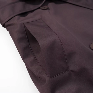 Gros plan de la poche en biais sur un trench-coat marron épais avec texture sergée