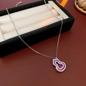 Close-up of a silver gourd necklace with pink gems and white crystals on a jewelry box
