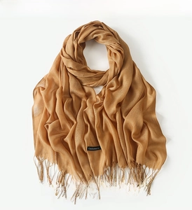 Detail view of caramel cashmere scarf texture with elegant fringes and woven labels