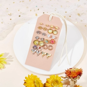 Tarjeta rosa para joyas con varios pendientes dorados y plateados en una bandeja blanca