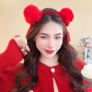 Close-up of a festive red plush ball headband with tassel charms on a female model