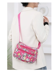 Detail of floral printed nylon crossbody bag showing multiple zipper pockets and strap