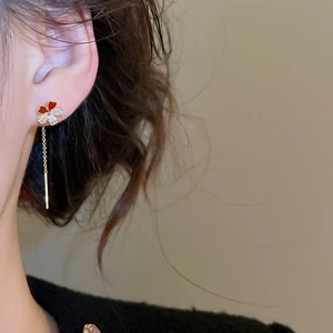 Detail of floral drop earrings with gold plating and zircons on a model's ear