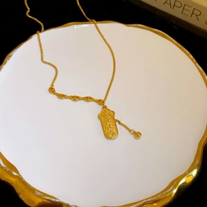 Dettaglio di una collana cilindrica dorata con benedizioni in rilievo su piatto di ceramica