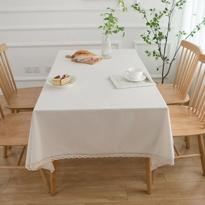 Natural white linen tablecloth with delicate lace borders on a rustic wooden table