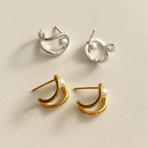 Detailed view of 925 silver pearl stud earrings in gold and silver finish on a textured background