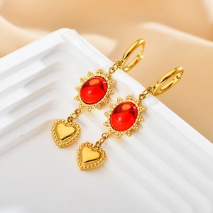 Dettaglio dei pendenti boho in oro con pietre rosse ovali e ciondoli a cuore lucidi