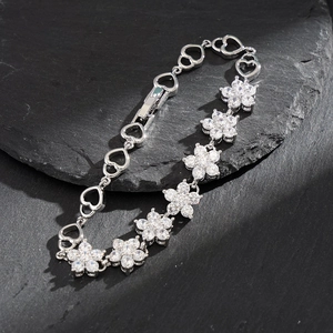Silver snowflake flower bracelet with AAA zircon heart links on a stone surface