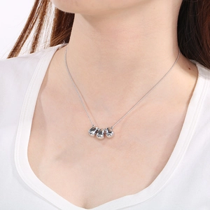Detailed view of three polished silver teardrop pendants on a delicate choker chain