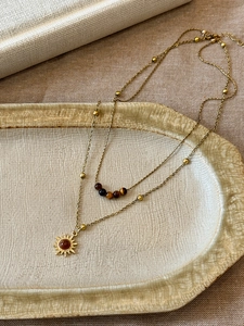 Detailed close-up of double-layer necklace with tiger eye beads and sun pendant