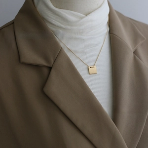 Detail of vintage square gold necklace with matte brushed finish and 1967 engraving