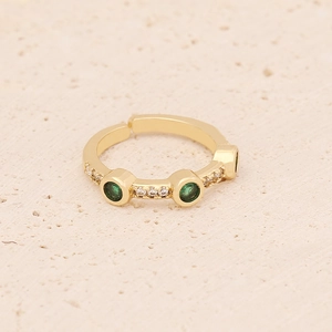 Detail of gold-plated ring with emerald green stone and sparkling white crystals
