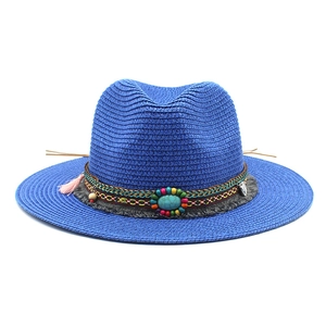 Detail van blauwe strooien fedora met een etnische band voorzien van turkoois en kwastjes
