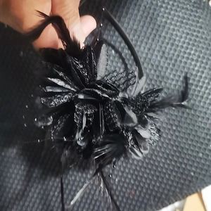 Detail of elegant black bridal fascinator with fabric flower clusters and soft feathers