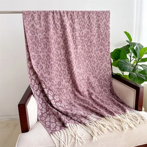 Detail of soft purple leopard jacquard scarf with cream tassels draped on a modern chair