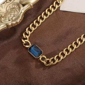 Detailopname van een gouden Cubaanse ketting met een vierkante blauwe kristallen steen