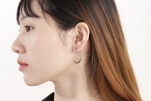 Close-up of a silver stainless steel large hoop earring worn by a female model
