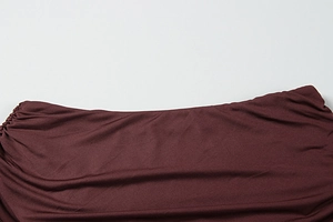 Gros plan sur la texture du tissu bordeaux et les détails froncés de la robe d'été chic