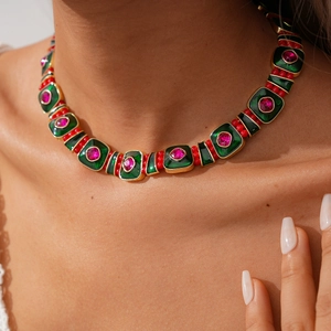 Gros plan d'un collier bohème avec carreaux en émail vert et cristaux roses sertis