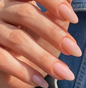 Close-up of glossy translucent almond-shaped press-on nails in soft nude pink