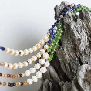 Ethnic necklace with colorful natural stones and freshwater pearls on gray rock background