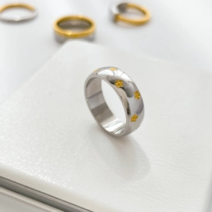 Detail of silver titanium steel ring featuring embossed gold stars on a polished surface