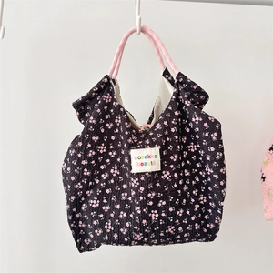 Close-up of black floral bubble fabric tote bag with pink rope handles and logo patch