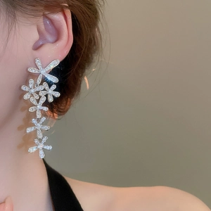 Close-up of silver tassel earrings featuring zircon flower petals worn by a model