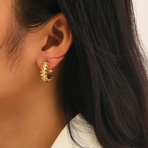 Close-up of a 18k gold plated stainless steel C-shaped earring with studded spike details
