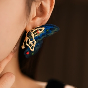 Détail de boucles d'oreilles papillon dorées vintage avec broderie bleue et cristaux