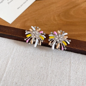 Detailed shot of floral firework stud earrings with crystals on a wooden stand