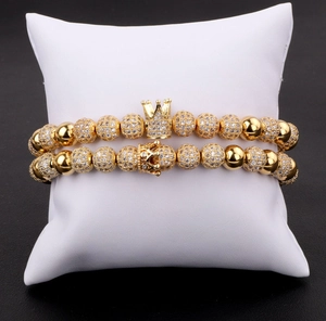Detail of luxury gold crown bead bracelets with micro-pave zircons on a white display pillow