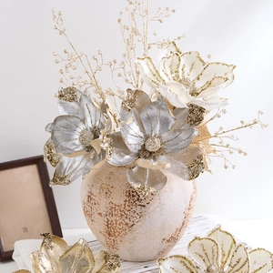 Sparkling silver and gold artificial magnolia flower arrangement in a vintage ceramic vase