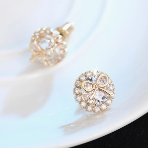 Macro shot of gold bow stud earrings with clear round cubic zirconia and pavé halo