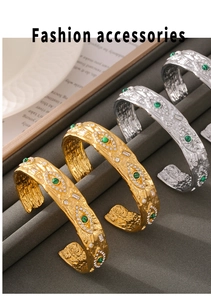 Nahaufnahme goldener und silberner Armreifen mit grünen Steinen und Hammerschlag