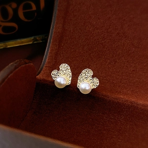 Detail of vintage heart-shaped gold stud earrings with white pearls on a velvet box