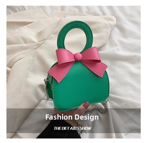 Detail shot of mini green crossbody bag featuring a pink bow and silver bead chain