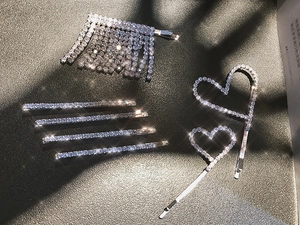 Coffret de pinces à cheveux argentées avec strass brillants et pompons sur fond gris